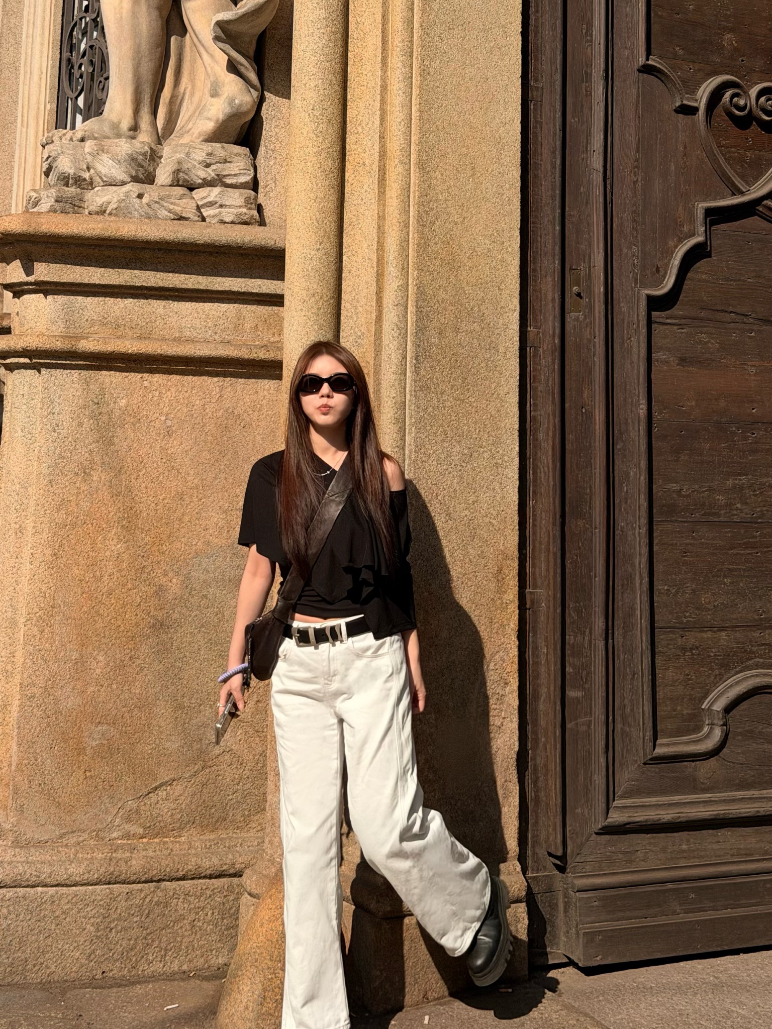 Shan standing beside stone columns in sunlight
