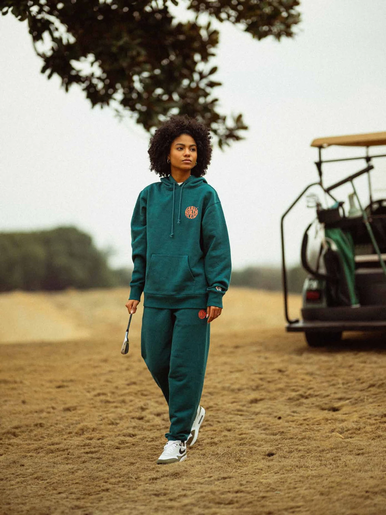 Model in a teal Early Birds Club tracksuit walking toward the camera